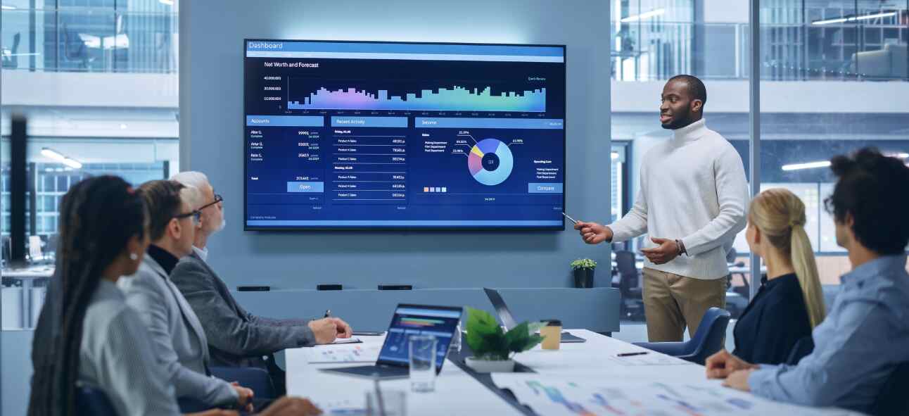 Office Conference Room Meeting Presentation: Black Businessman Talks, Uses TV Screen to Show Company Growth with Big Data Analysis, Graphs, Charts, Infographics. e-Commerce e-Business.