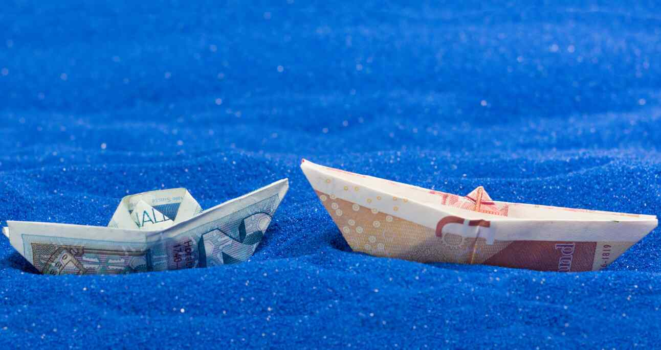 Two paper boats made of two different currency notes to represent cross border payments